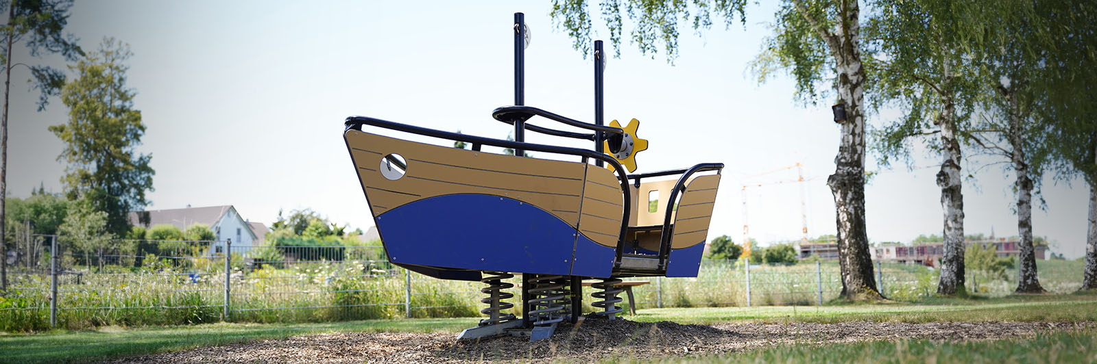 A large springer for playgrounds, it's shaped like a small boat with anchor and sail with a small wheel inside for imaginative play.